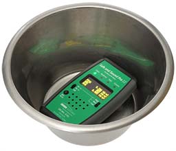 A green microwave meter in the bottom of a metal bowl.